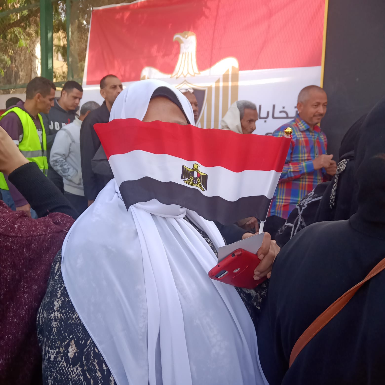 امرأة تحمل العلم المصري أمام لجنتها الانتخابية