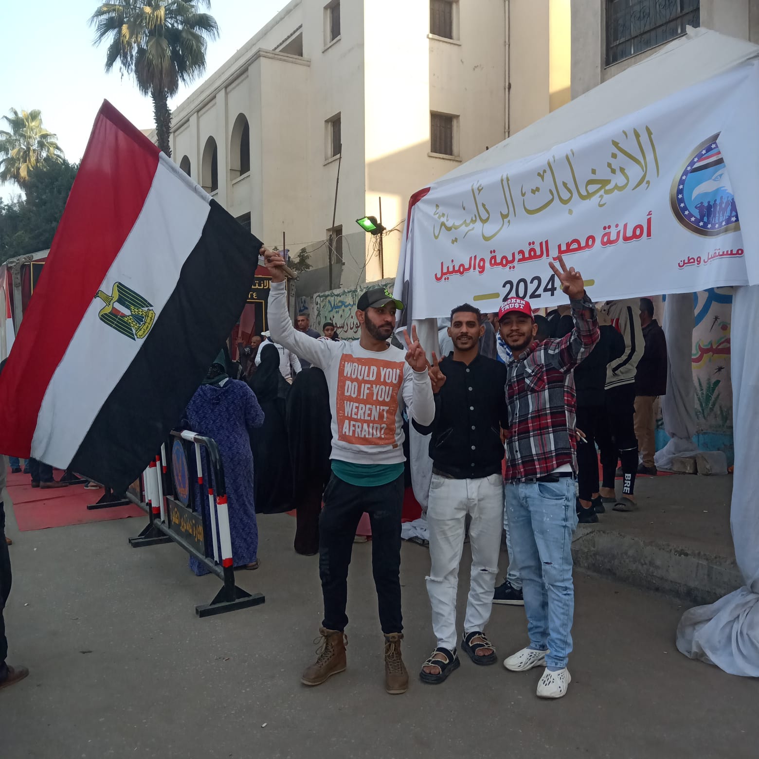 شباب يرفعون العلم المصري عالياً أمام اللجان الانتخابية